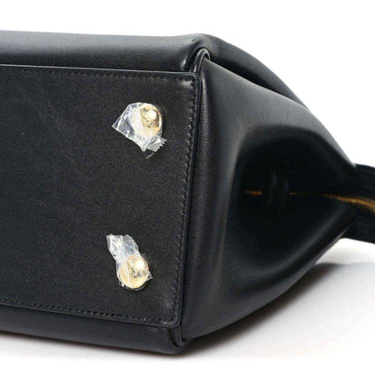 Black leather handbag corner with two gold-tone studs and stitched edge