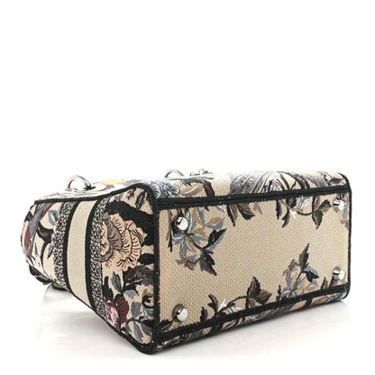 Floral canvas handbag with striped band and silver-tone studs, side view.