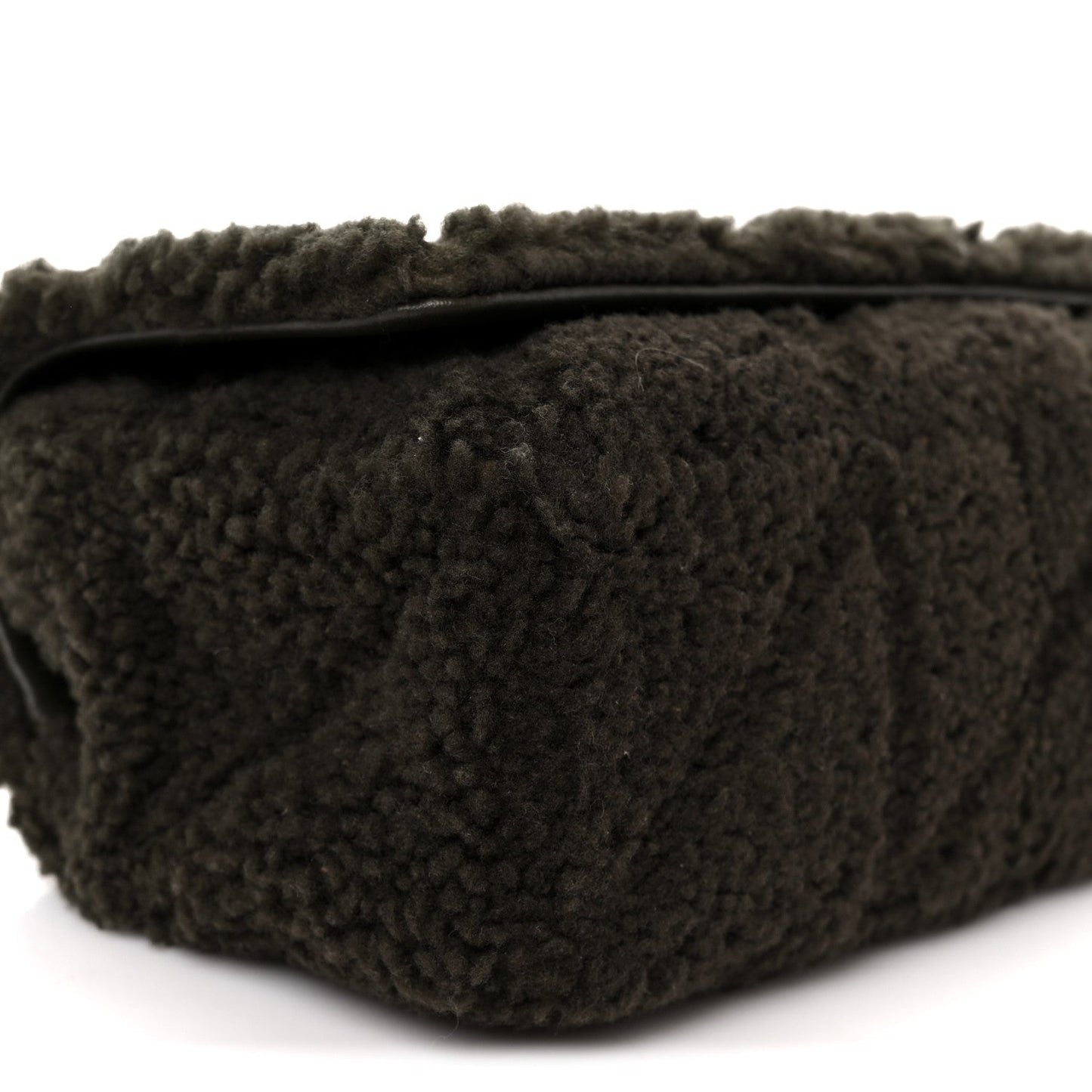 Dark shearling shoulder bag with top edge and stitched seams, close-up