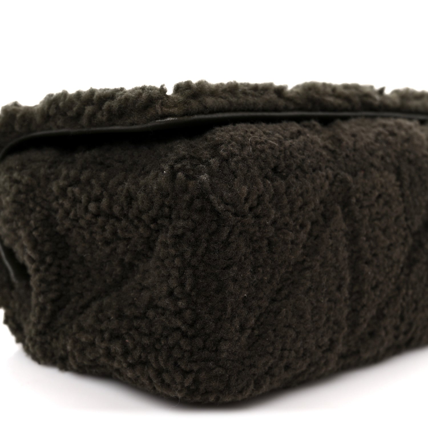 Dark shearling shoulder bag with top edge and stitched seams, close-up
