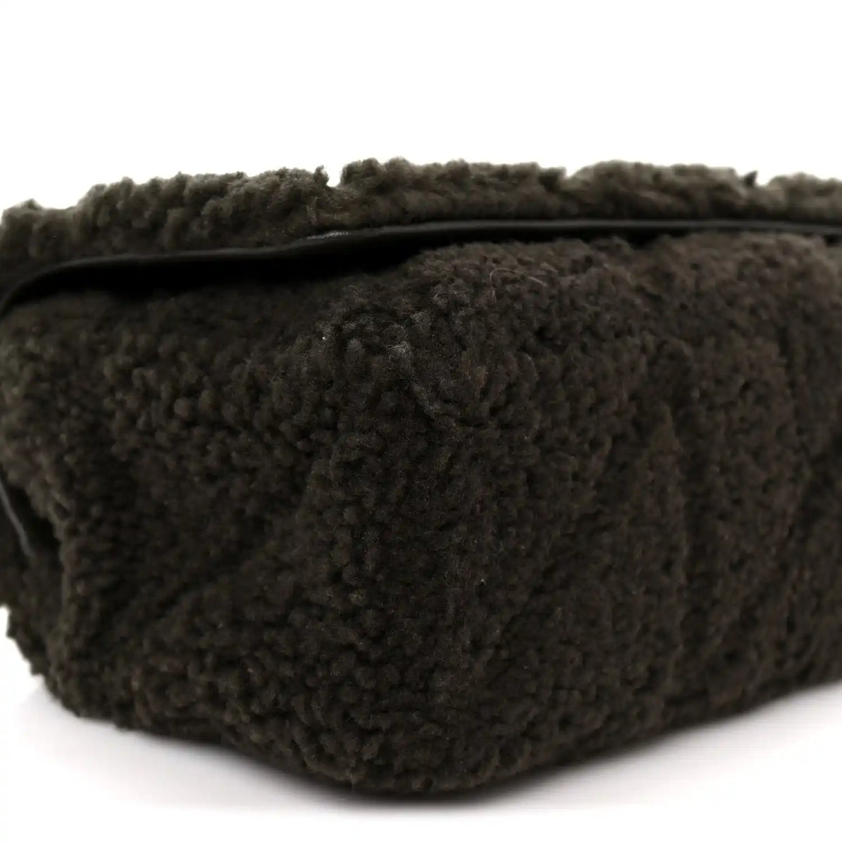 Dark shearling shoulder bag with top edge and stitched seams, close-up
