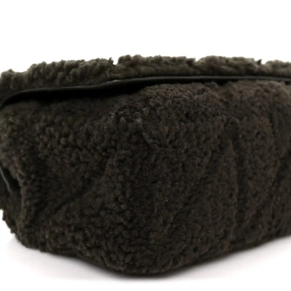 Dark shearling shoulder bag with top edge and stitched seams, close-up