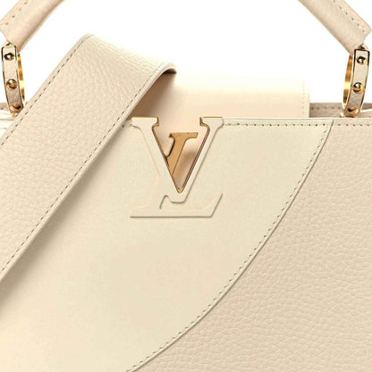 Beige leather handbag front with embossed V logo, top handles, and gold-tone rings