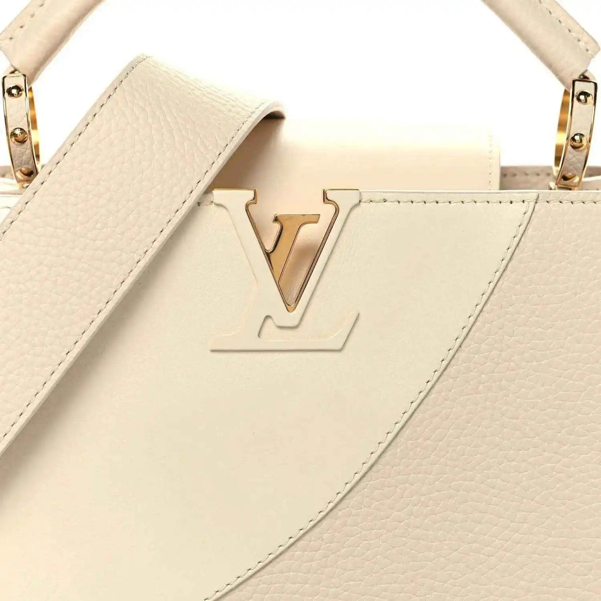Beige leather handbag front with embossed V logo, top handles, and gold-tone rings