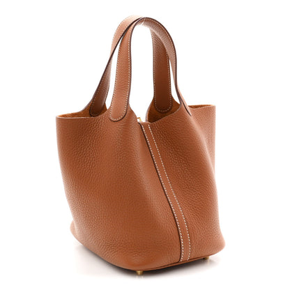 Tan leather bucket bag with curved handles and gold-tone base hardware