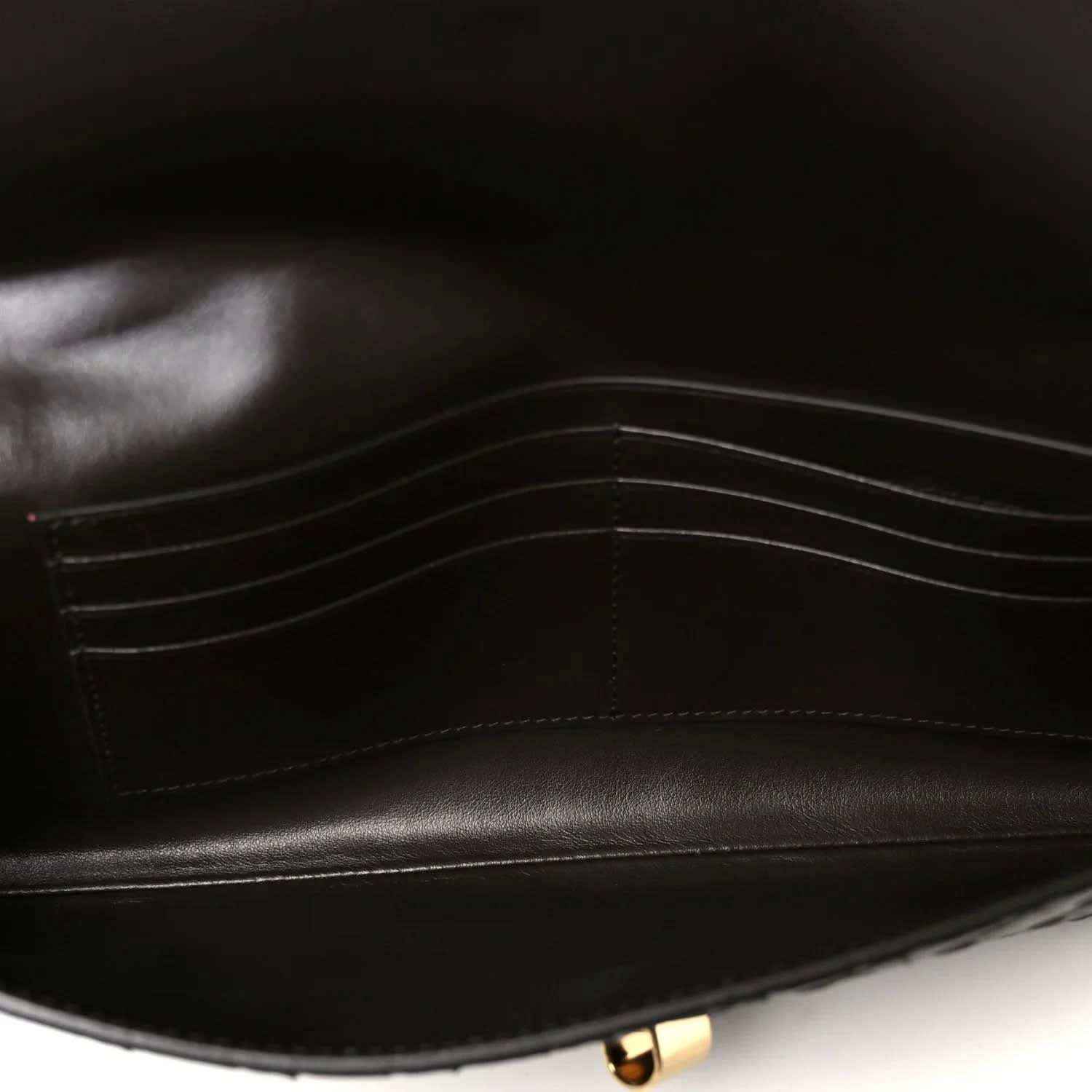 Dark leather clutch interior with stitched lining and gold-tone clasp hardware