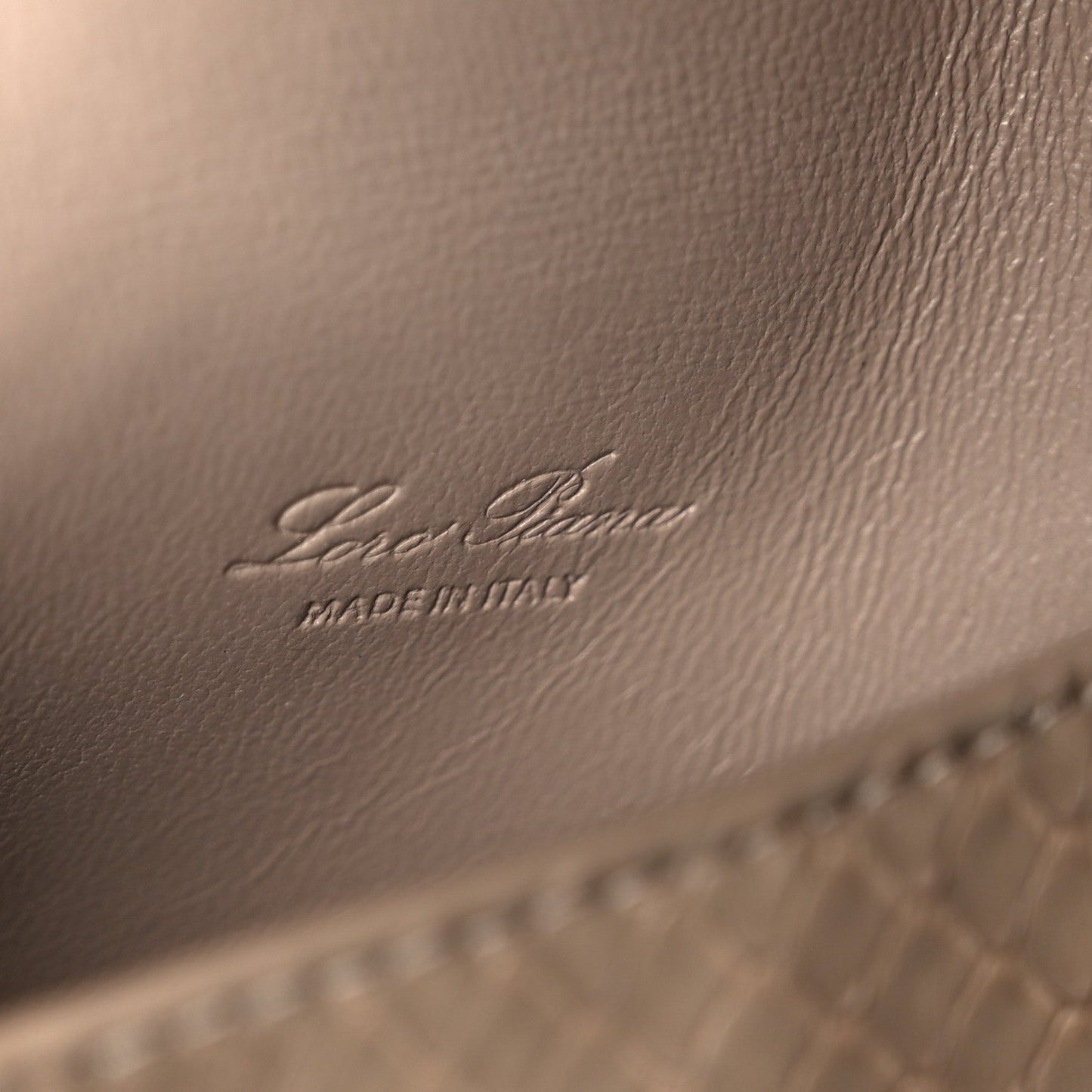 Matte snakeskin handbag close-up of embossed Loro Piana logo on front panel