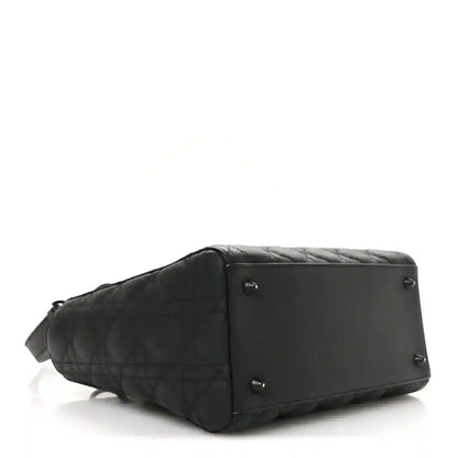 Black quilted Lady Dior bag with structured base and side panel hardware, profile view