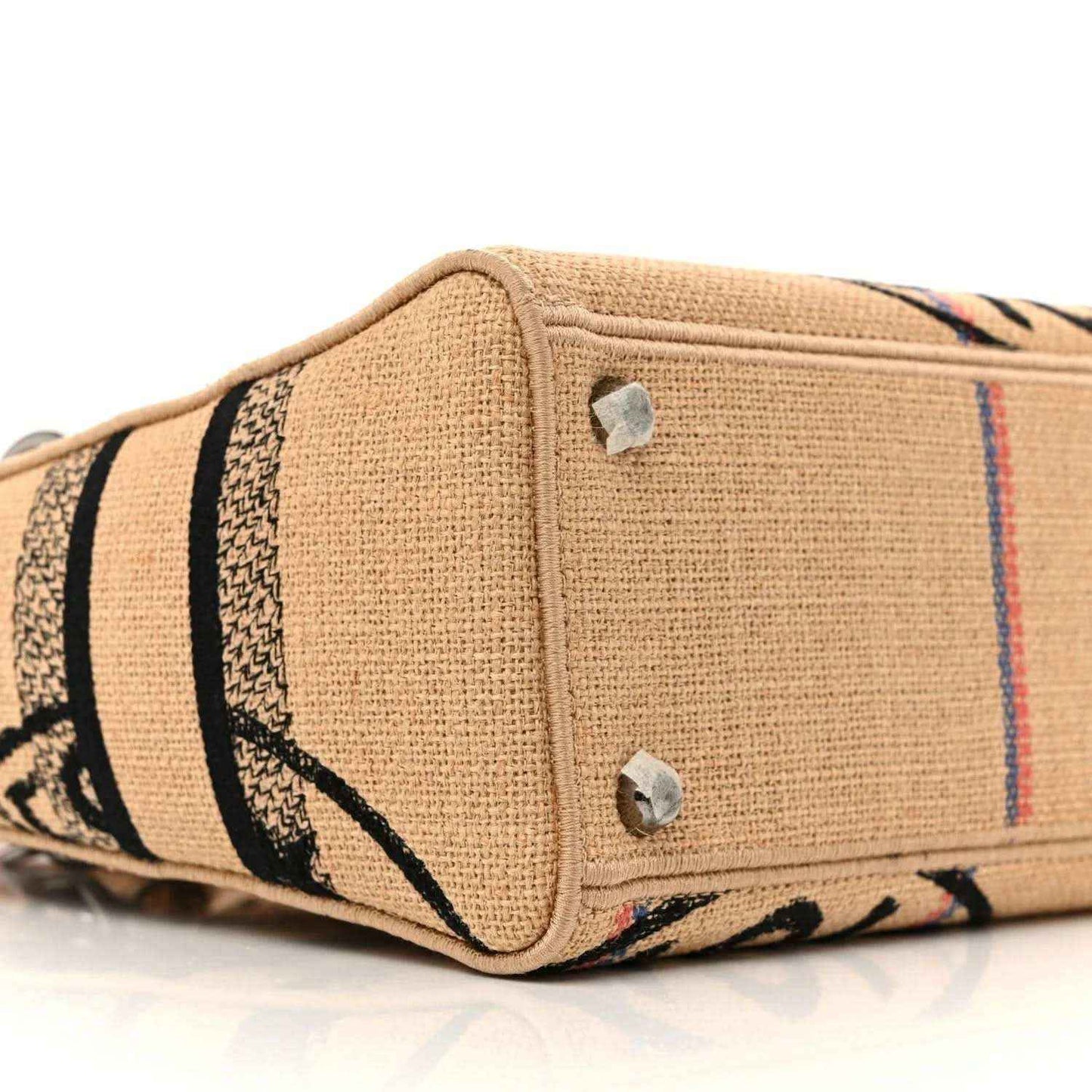 Jute canvas bag side view with striped embroidery and two silver snap details.