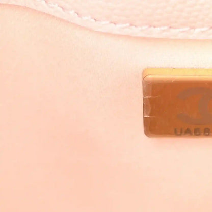 Light pink quilted leather mini handbag edge close-up with gold-toned logo tab