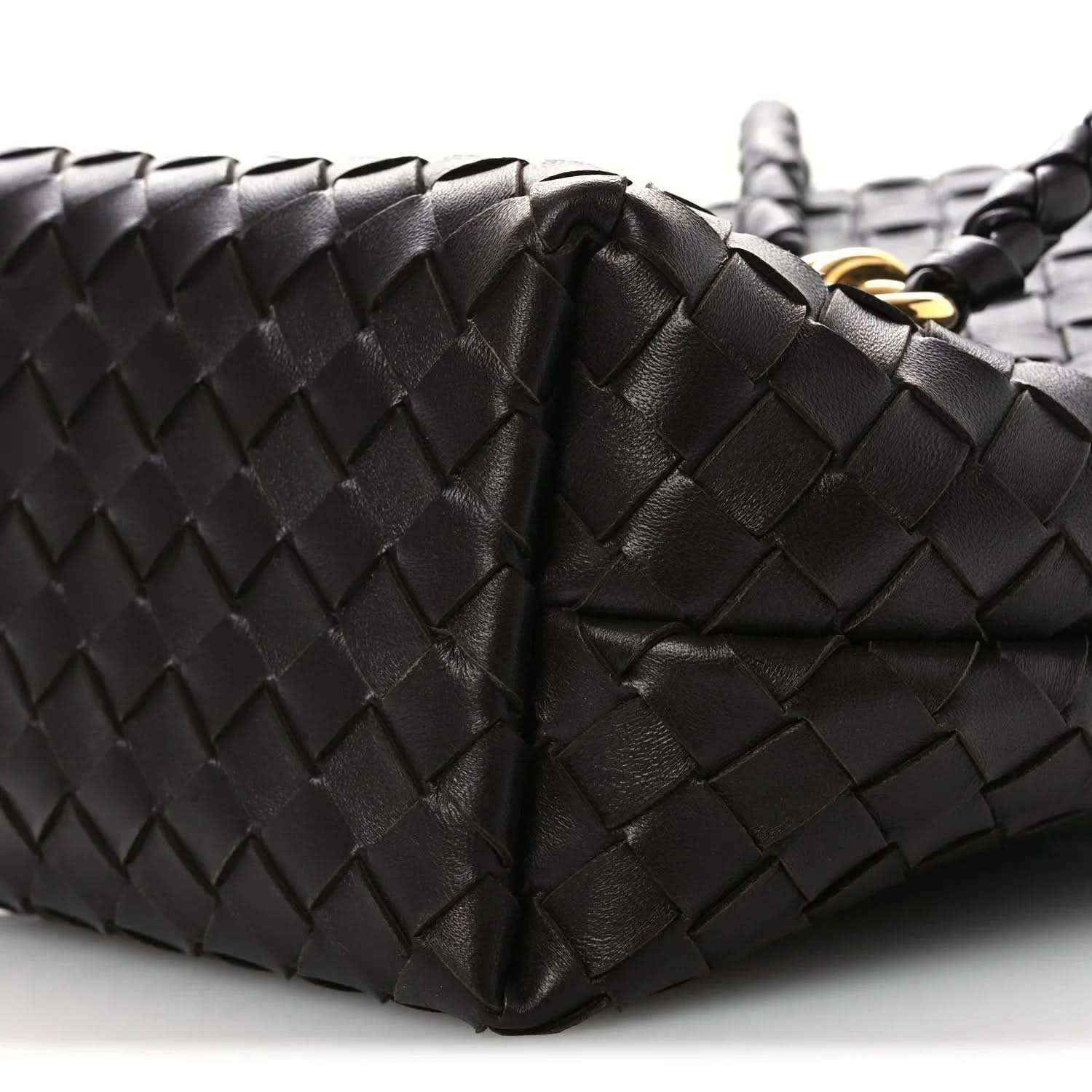 Intrecciato leather bucket bag close-up, dark color, woven panels and handle seam
