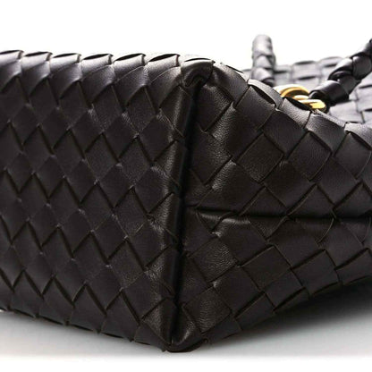 Intrecciato leather bucket bag close-up, dark color, woven panels and handle seam