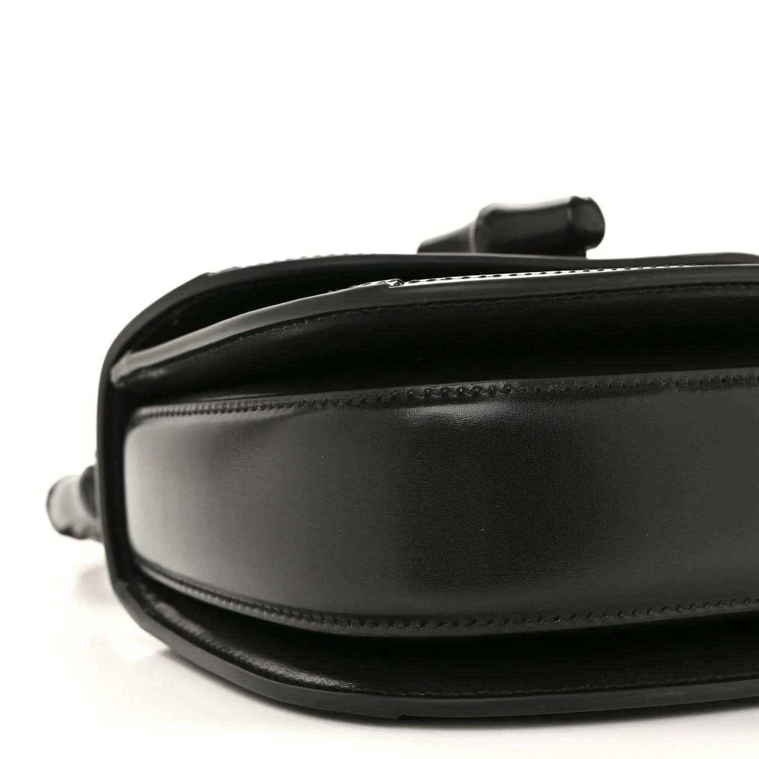 Black mini handbag close-up of side panel with smooth leather and stitching.