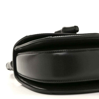 Black mini handbag close-up of side panel with smooth leather and stitching.