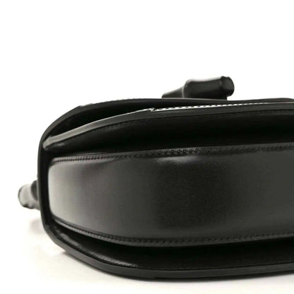 Black mini handbag close-up of side panel with smooth leather and stitching.