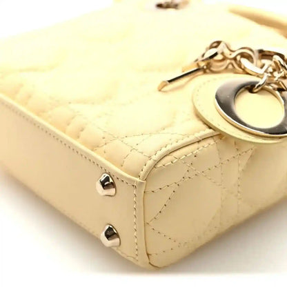 Soft yellow handbag side detail with cannage quilting, strap, and metal stud feet