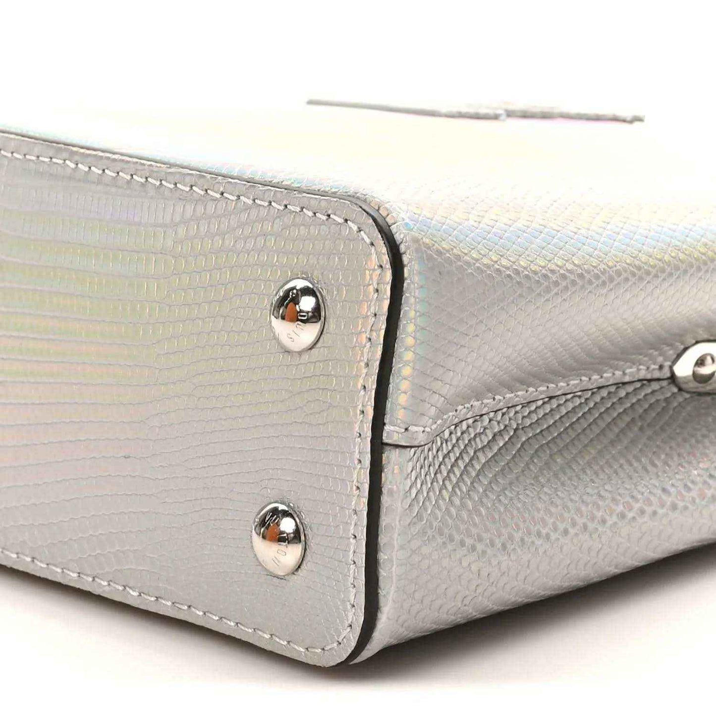 Iridescent lizard mini handbag side close-up with silver rivets and curved trim