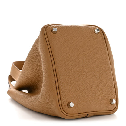 Tan leather bucket bag with grommet hardware and folded top edge