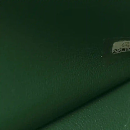 Green leather bag close-up with textured surface and small serial label tag.