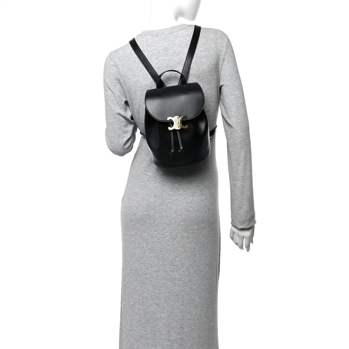Celine Triomphe calfskin Bonnie backpack, black, worn over a long-sleeve dress.
