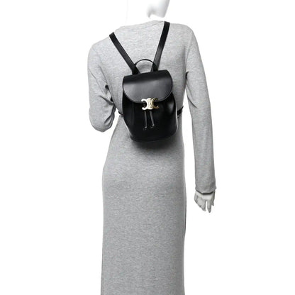 Celine Triomphe calfskin Bonnie backpack, black, worn over a long-sleeve dress.