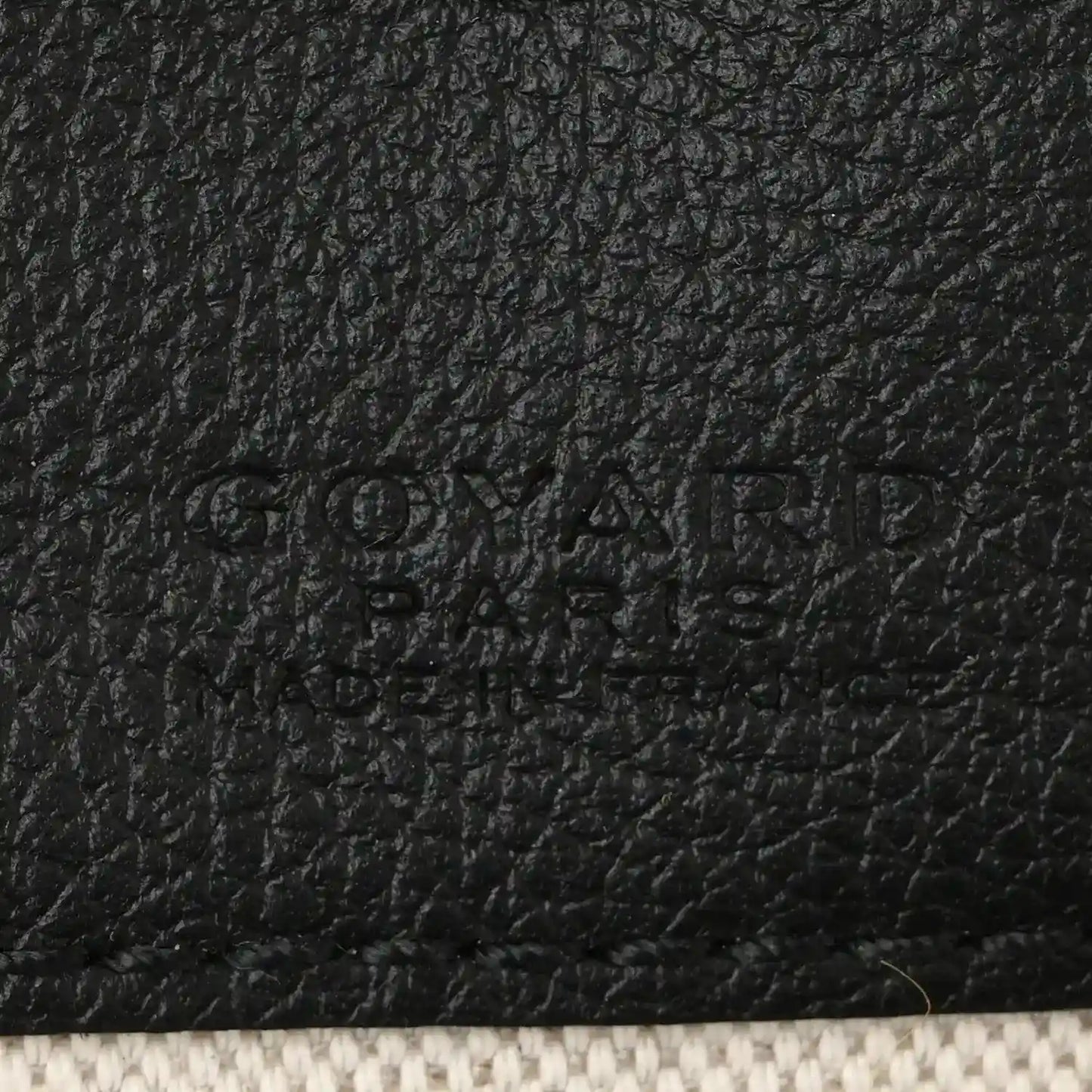 Black leather patch detail with embossed brand text on shoulder bag