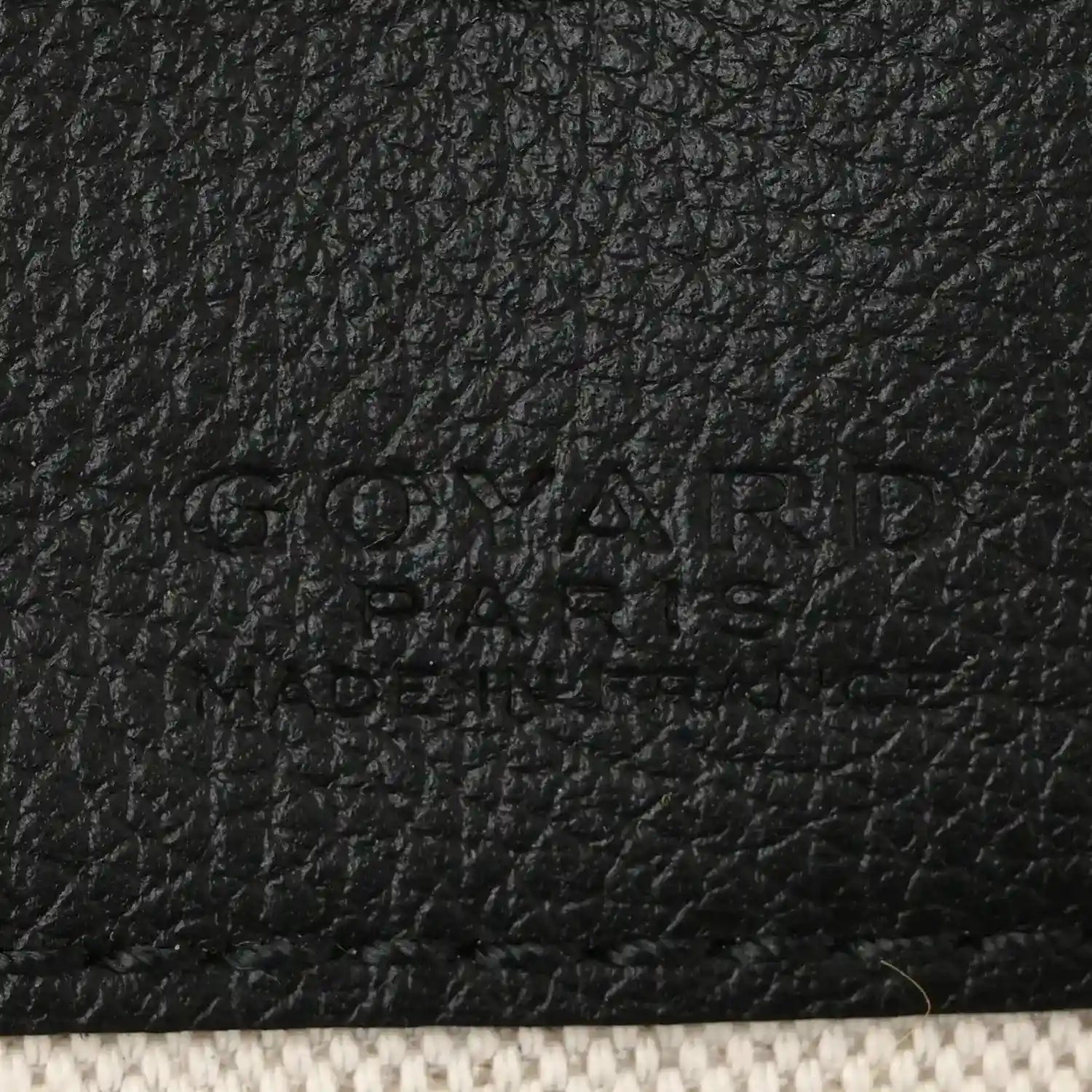 Black leather patch detail with embossed brand text on shoulder bag