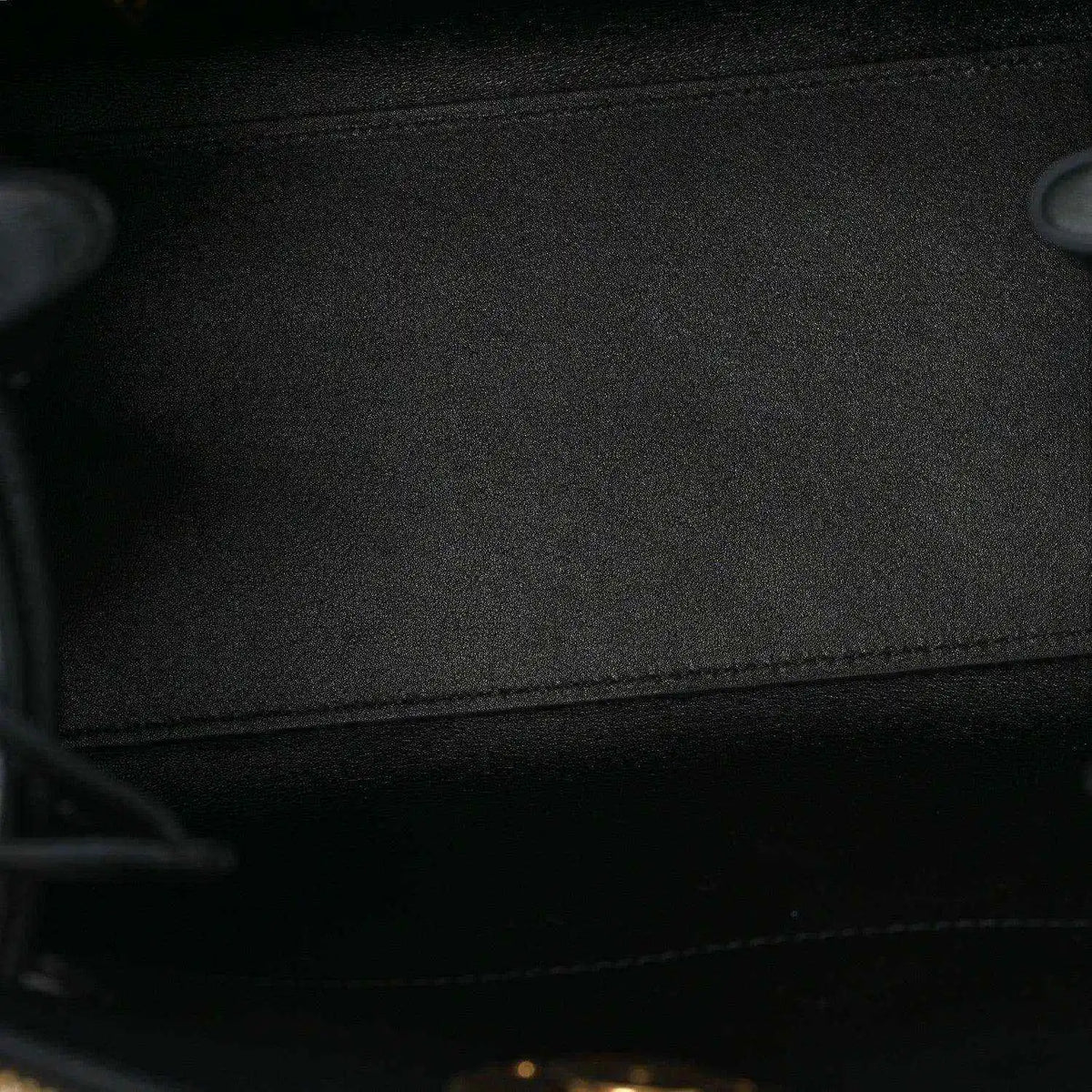 Black fabric lining inside a small leather handbag