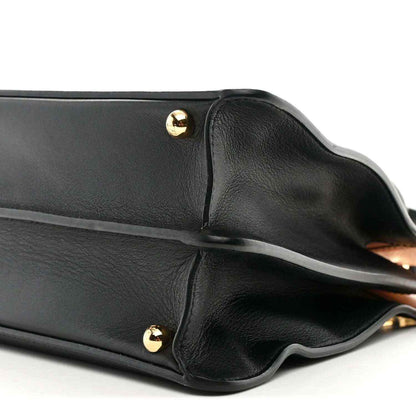 Medium black leather satchel side view with gold-tone studs and peekaboo-style flap