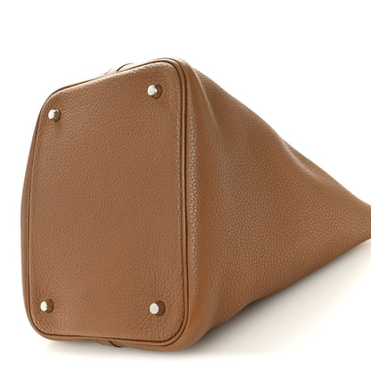 Tan leather tote side close-up with metal corner studs and structured form