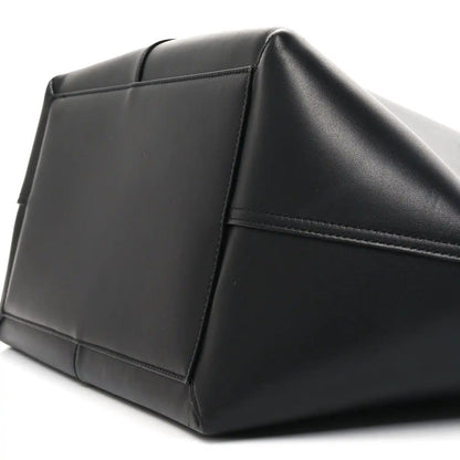 Black smooth calfskin trapezoid tote side panel with stitched seams and curved base