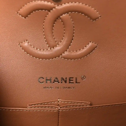 CHANEL logo on brown leather interior panel with stitched quilting and flap seam.