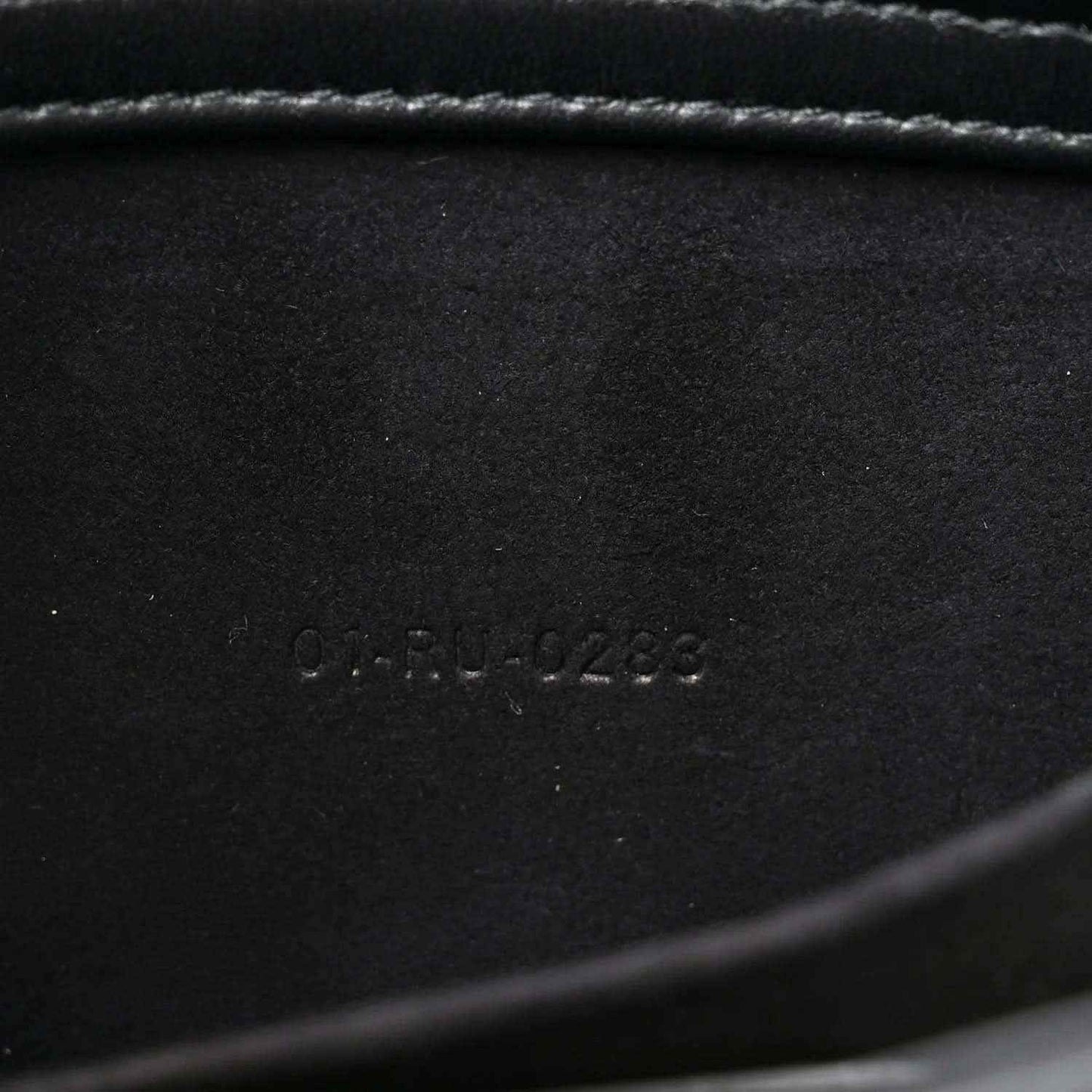 Embossed serial number on black interior panel of quilted handbag