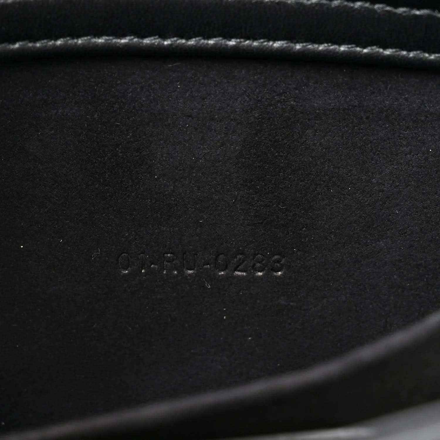 Embossed serial number on black interior panel of quilted handbag