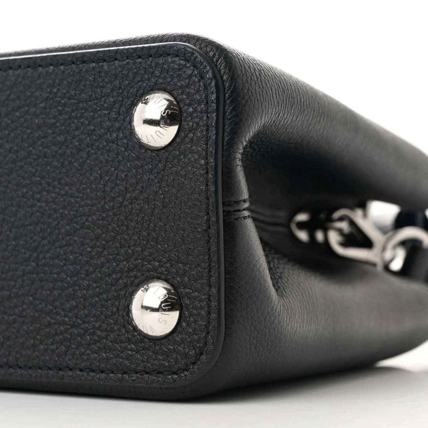 Black leather handbag end panel with two silver snap buttons and chain-link detail