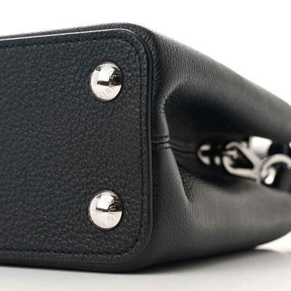 Black leather handbag end panel with two silver snap buttons and chain-link detail