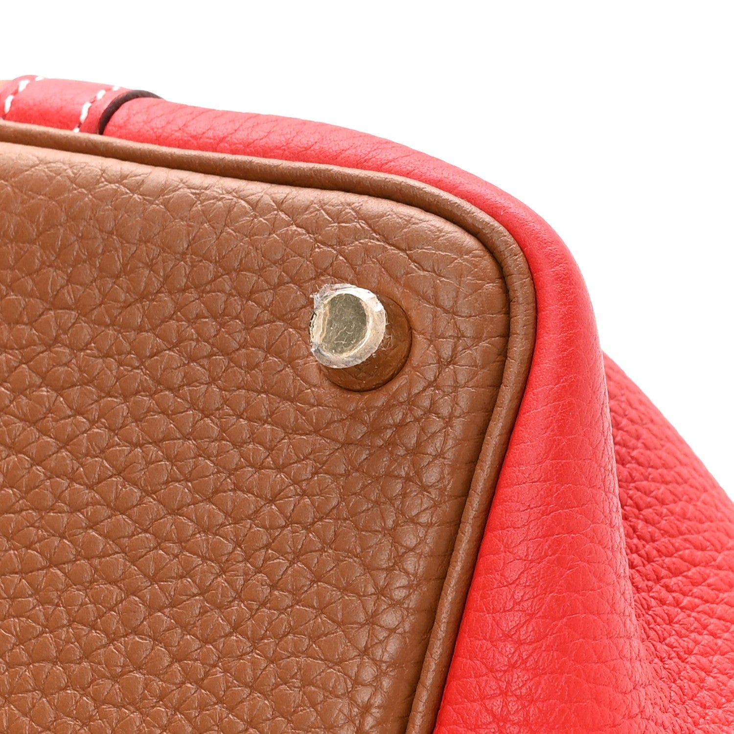 Brown leather panel with round metal snap and red trim, close-up