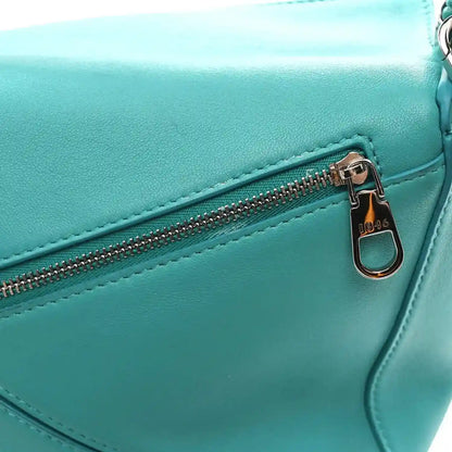 Teal-blue small Puzzle bag close-up of front zipper pull and gold-toned hardware.