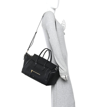 Black leather luggage bag with shoulder strap and front zip pocket.