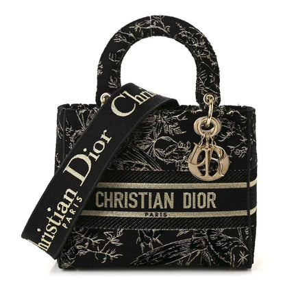 Black embroidered handbag with gold toile de jouy pattern, top handles, and Dior ribbon strap