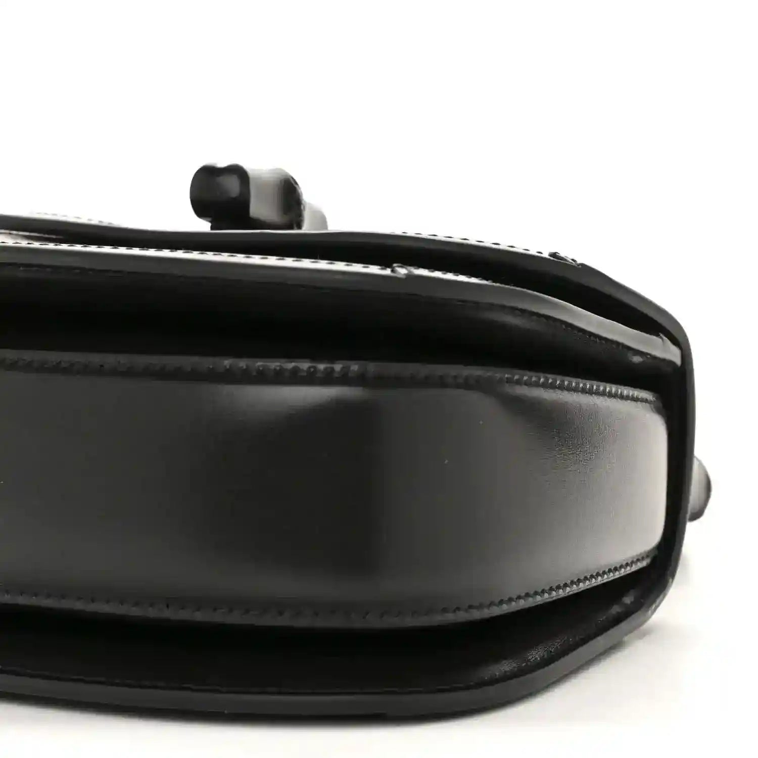 Black mini handbag side close-up with chain handle mount and glossy trim.