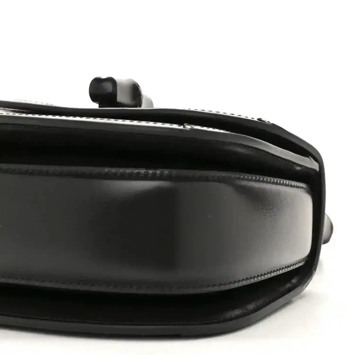 Black mini handbag side close-up with chain handle mount and glossy trim.