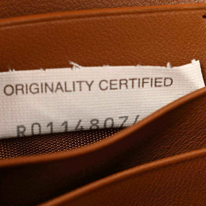 Clutch interior label with text “ORIGINALITY CERTIFIED” beneath stitched trim