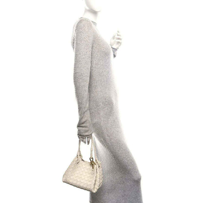 Light cream woven shoulder bag with braided strap and gold clasp, side view