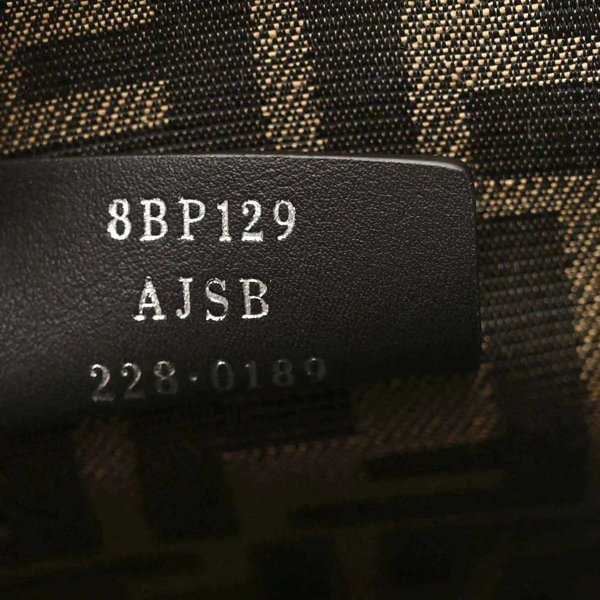 Clutch interior tag with “8BP129” and “AJSB” printed on leather