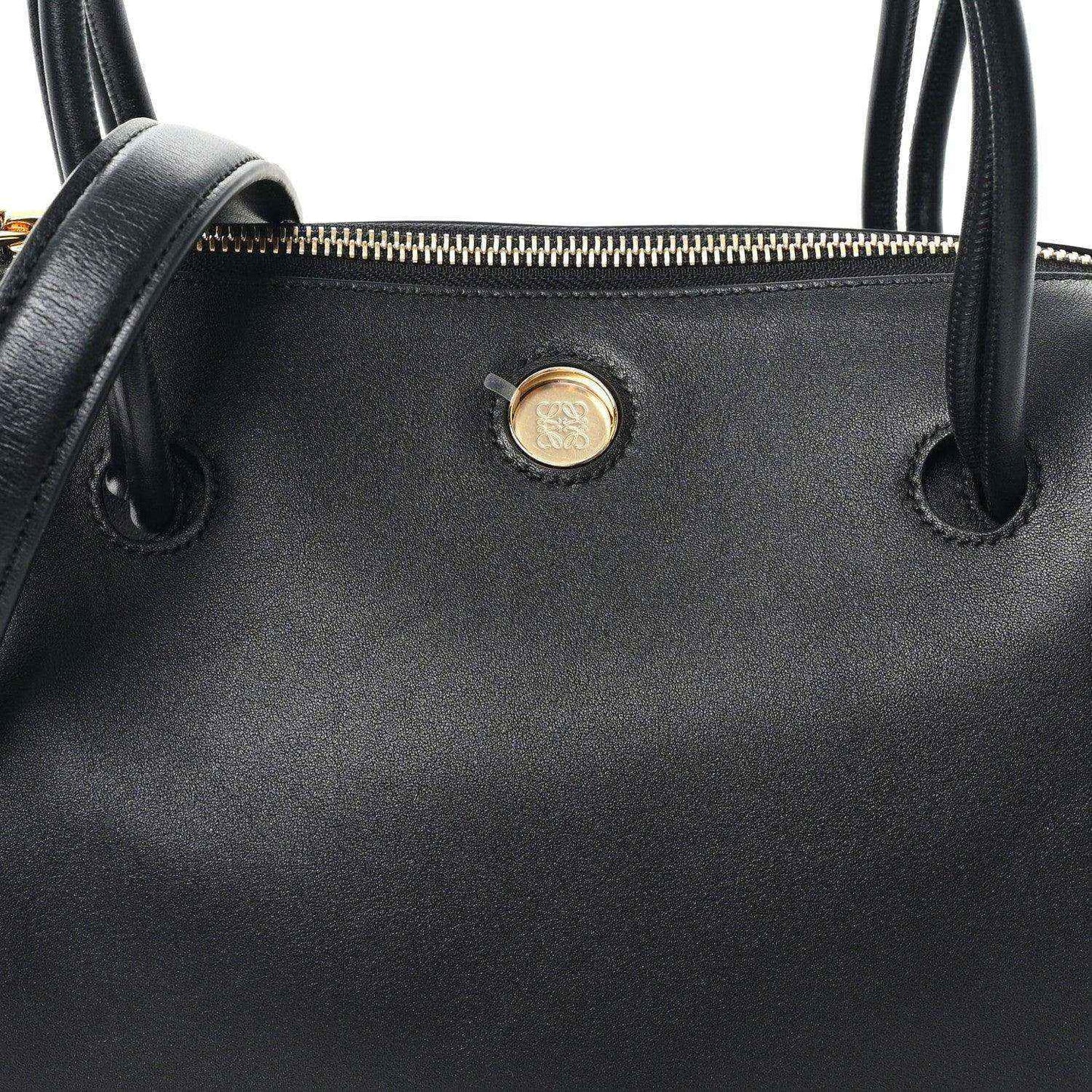 Black leather bag front with gold-tone button and top handle loops