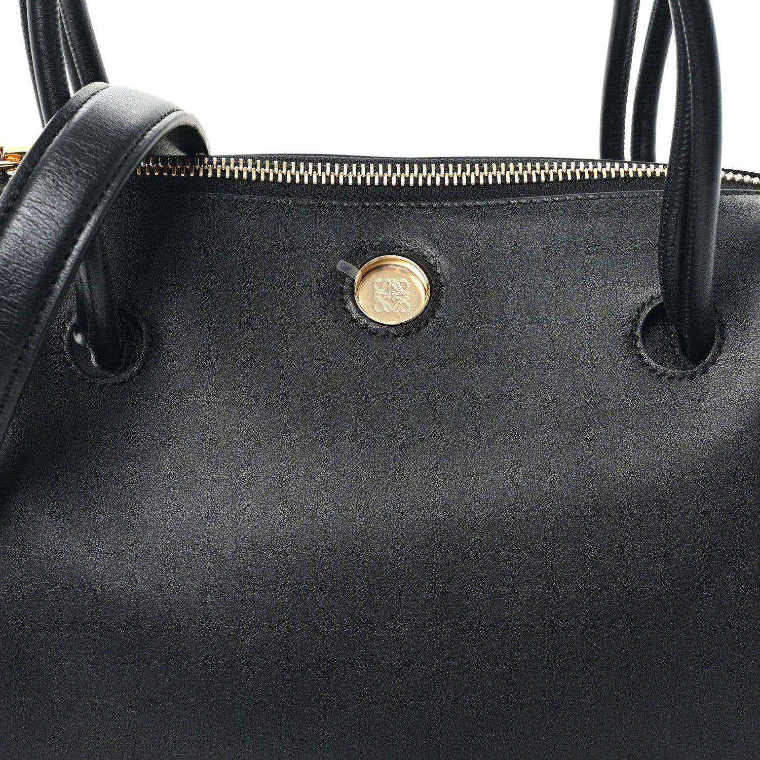 Black leather bag front with gold-tone button and top handle loops
