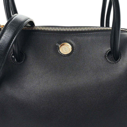 Black leather bag front with gold-tone button and top handle loops