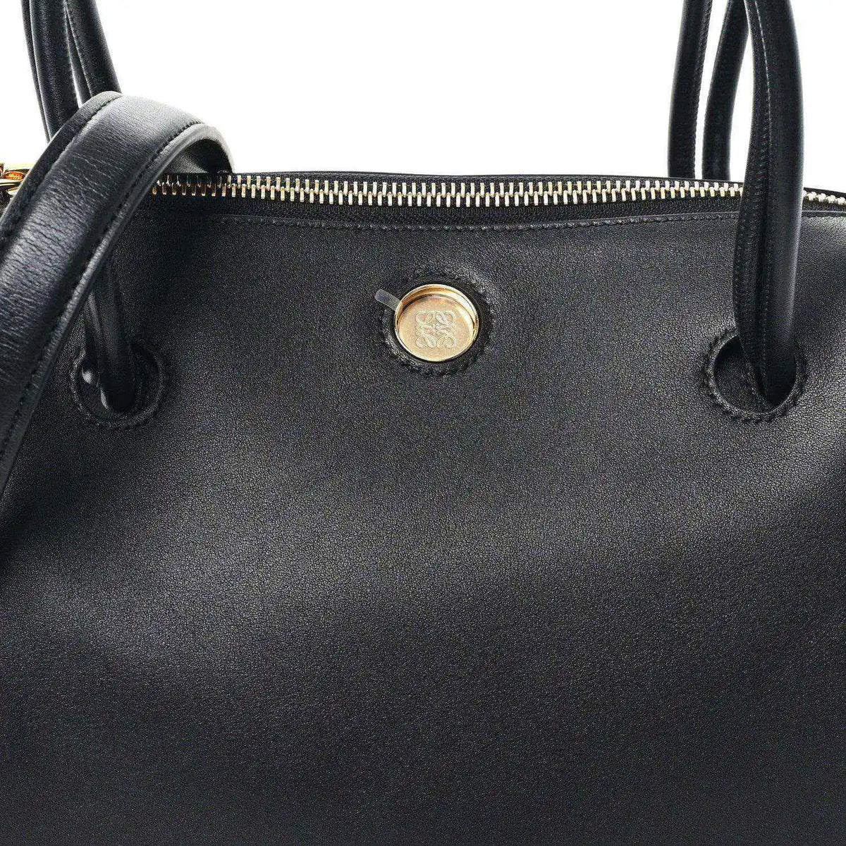 Black leather bag front with gold-tone button and top handle loops