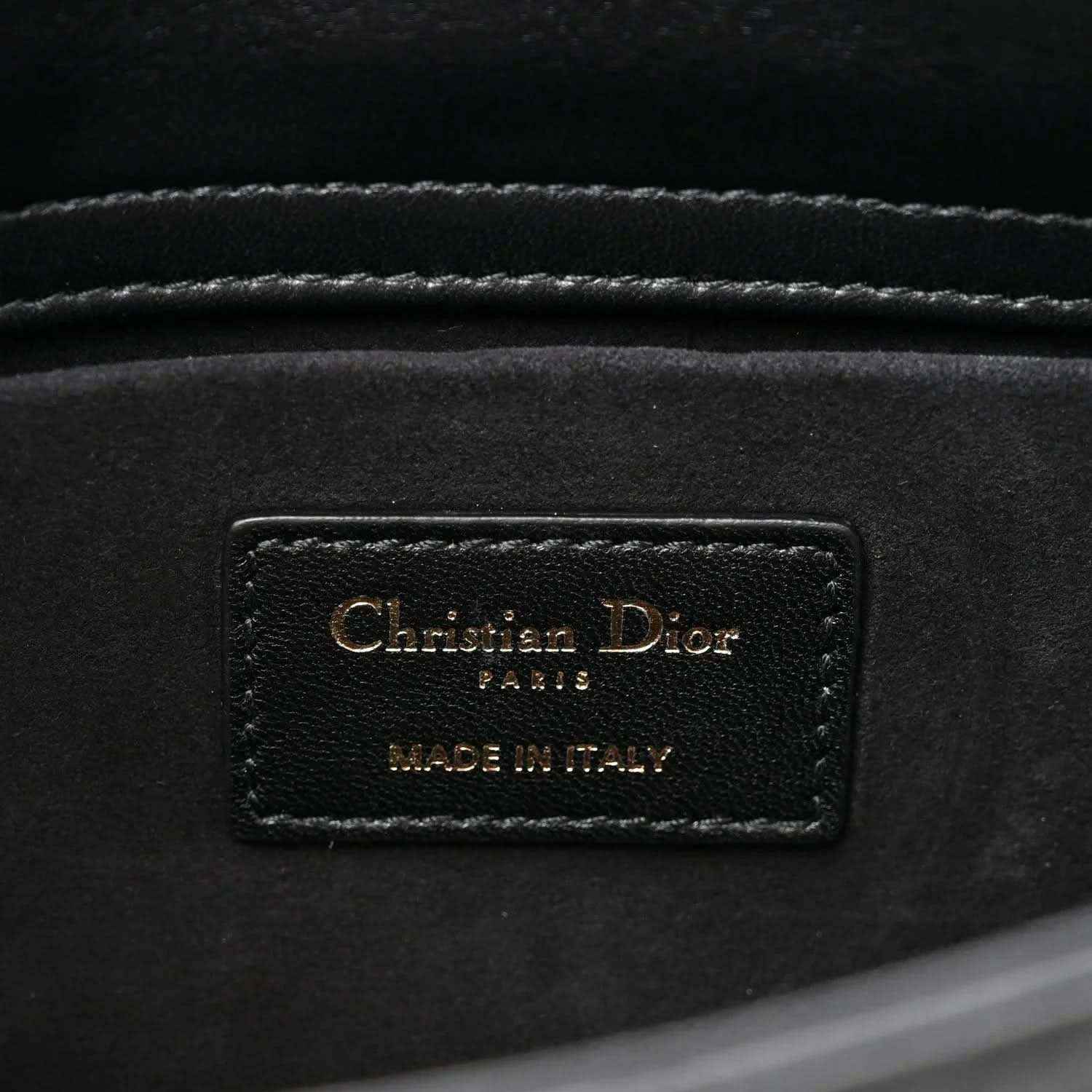Interior brand label on black quilted handbag reading Christian Dior and MADE IN ITALY